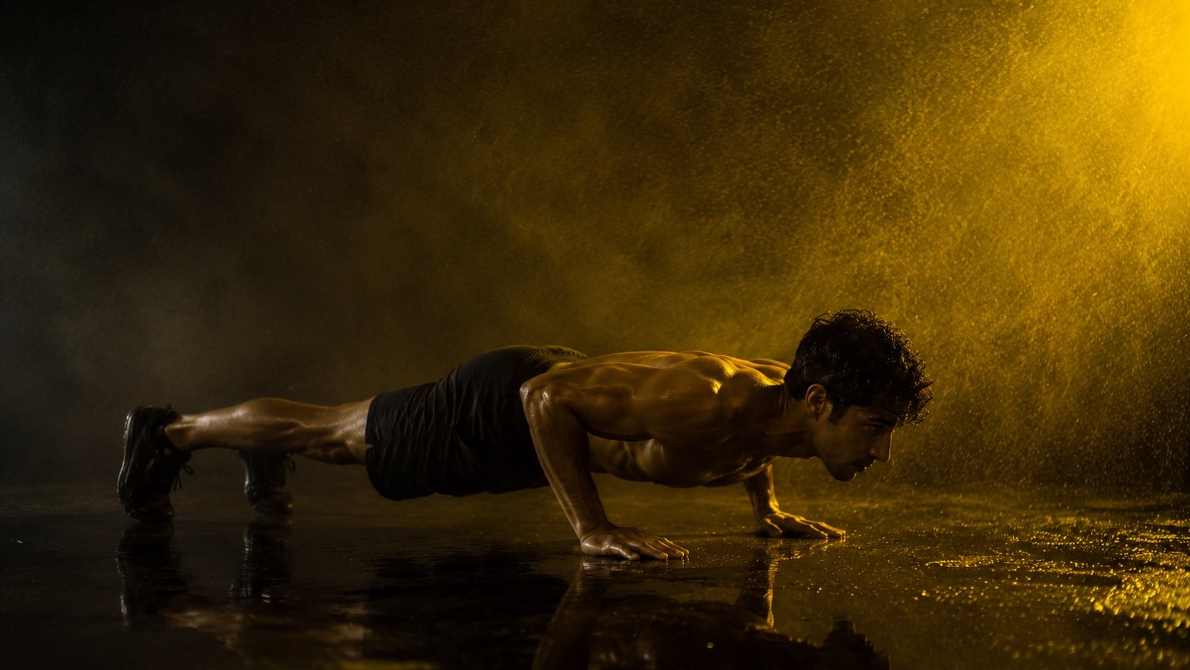 Athlete at the bottom of a push-up on a wet floor, backlit through falling spray